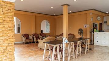Amplia habitación con una pared de acento de piedra, muebles de mimbre, una mesa de comedor con taburetes tipo bar y un armario blanco.