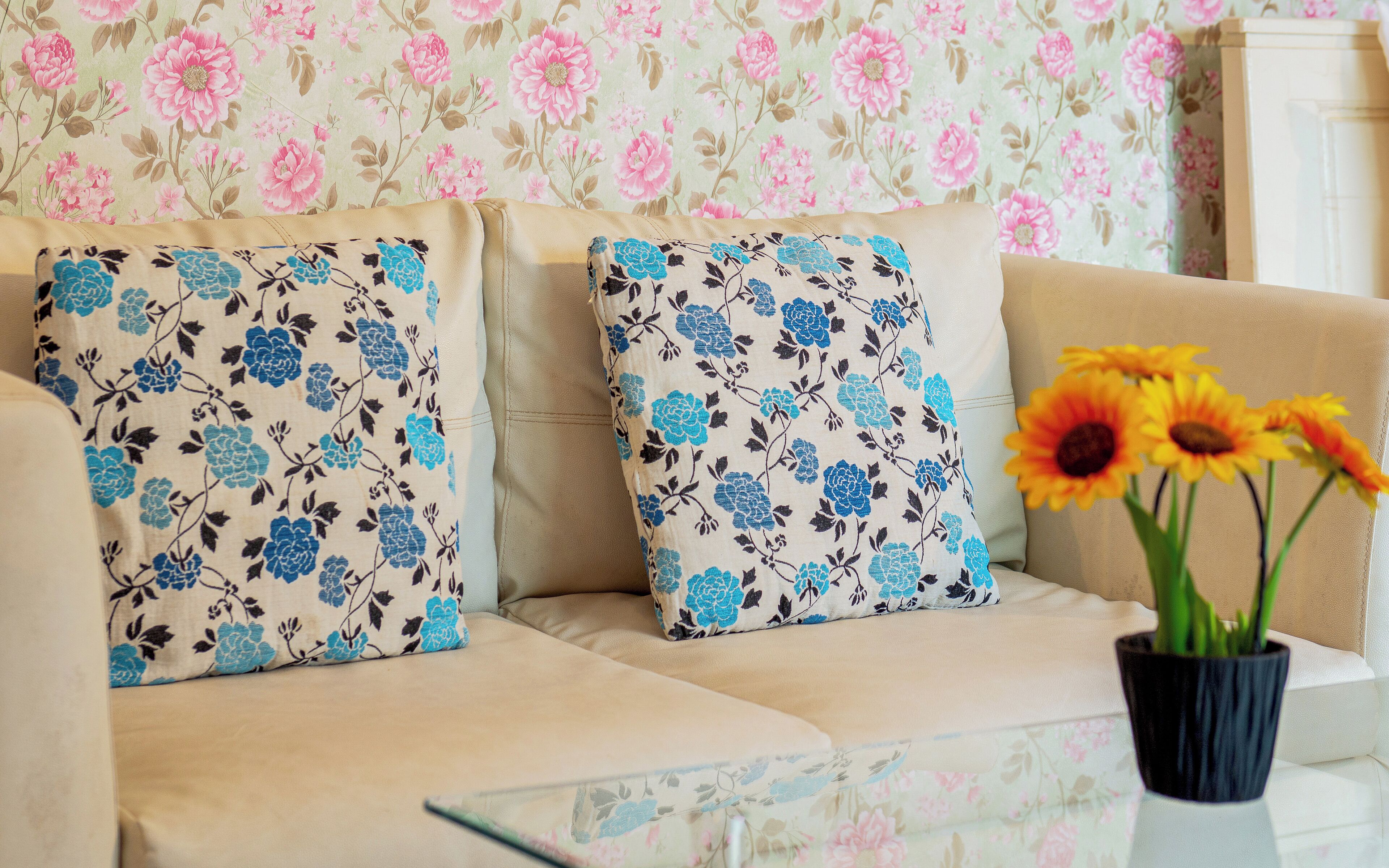 Un sofá con cojines estampados y un florero con flores.