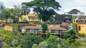 A hillside residential area with houses featuring balconies and a large tree in the center. - Samprasob Resort (Sangkhla Buri)