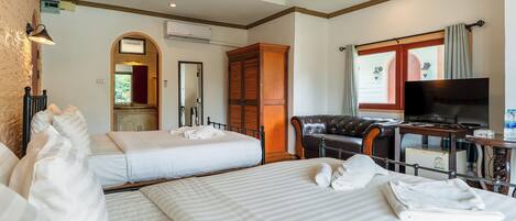 A hotel room with two beds, a television, a desk, and a leather chair.
