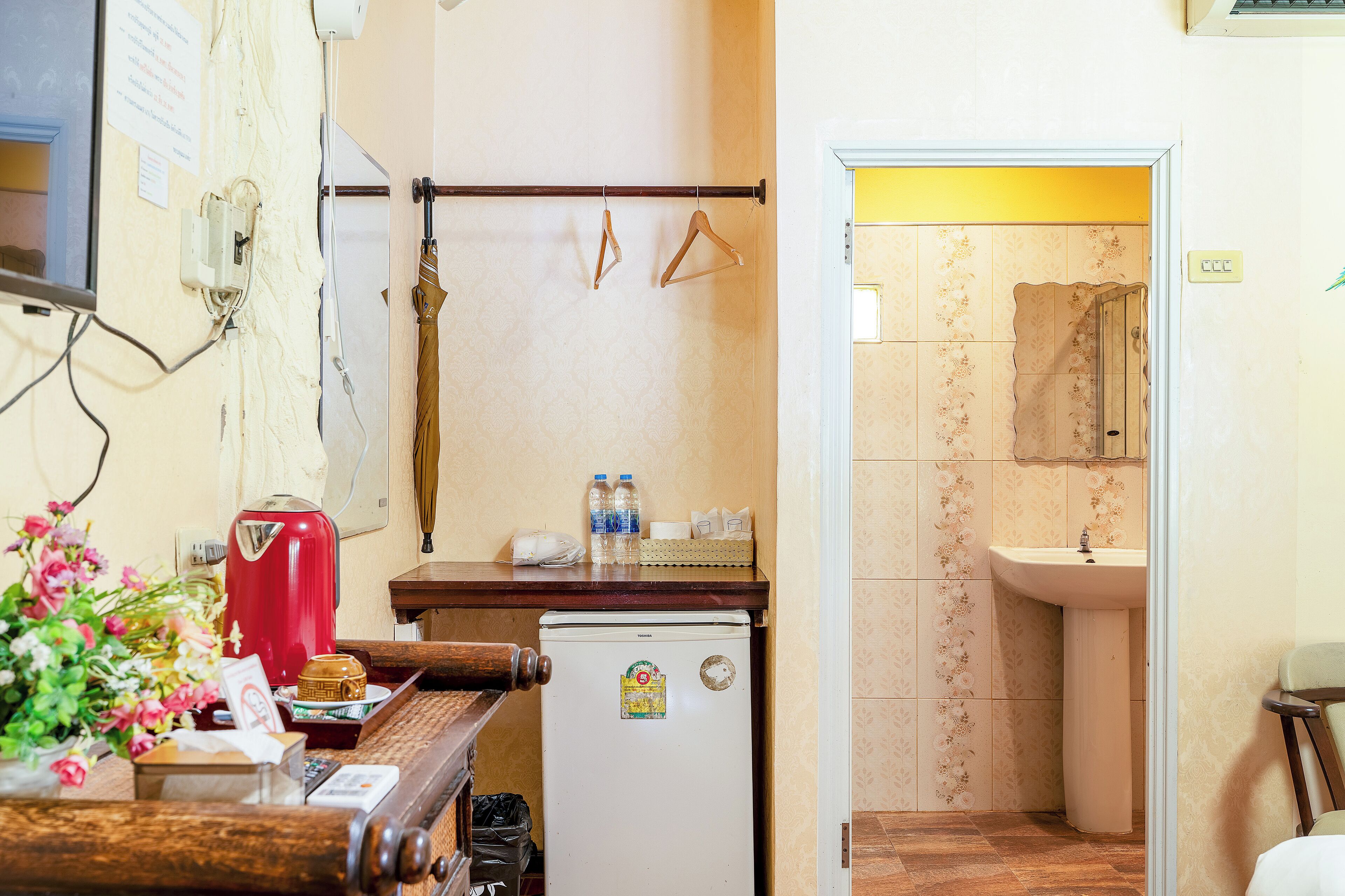 A compact kitchen with a refrigerator, a coffee maker, and a wooden counter.