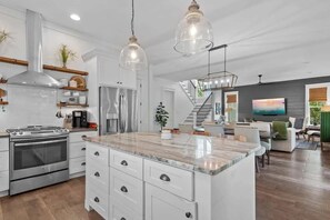Uma cozinha moderna com uma ilha grande, eletrodomésticos de aço inoxidável e iluminação pendente.