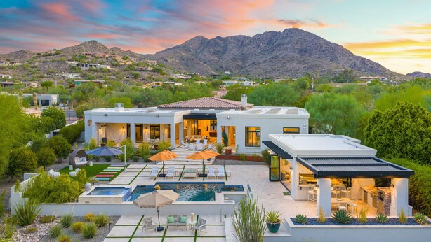 A modern house with a pool, outdoor seating, and a mountain backdrop.
