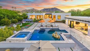 A modern house with a pool, outdoor seating, and a view of mountains.