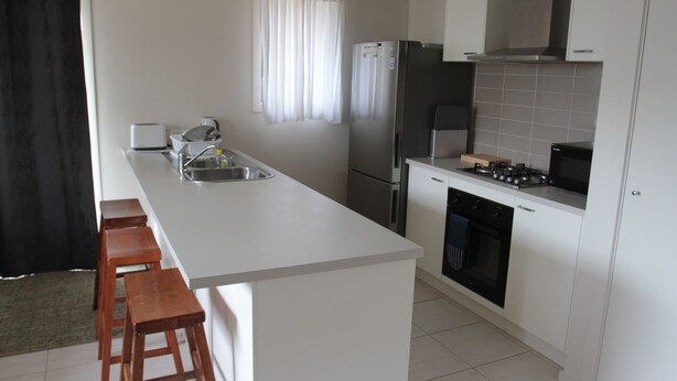 A modern kitchen with a central island, stainless steel appliances, and white cabinetry.