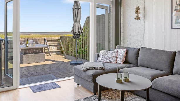 A modern living room with a grey sofa, a round coffee table, and a glass door leading to an outdoor patio. - "Kjera" - 2.4km from the sea by Interhome (Rømø)