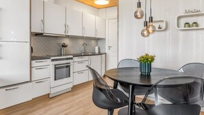 A modern kitchen with white cabinets, a built-in oven, and a dining area with a round table and chairs. - "Kjera" - 2.4km from the sea by Interhome (Rømø)
