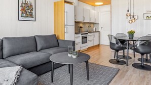 A modern apartment with a grey sofa, a small round table, and a kitchen area with white cabinets and a wooden ceiling. - "Kjera" - 2.4km from the sea by Interhome (Rømø)
