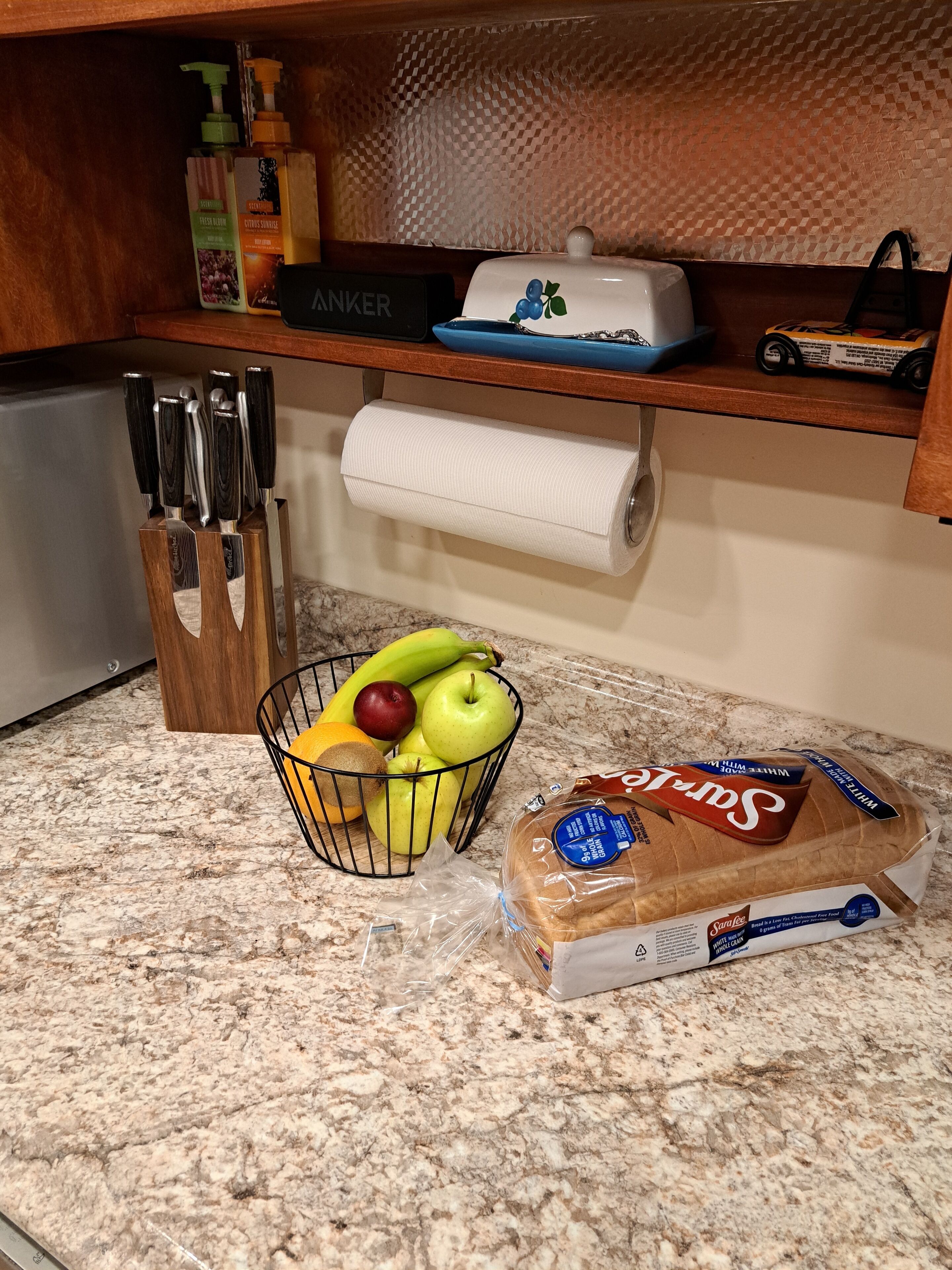 Een aanrecht met een fruitmand, een brood en een rol keukenpapier.
