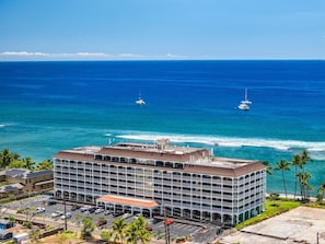 A multi-story hotel with a flat roof, located near a beach with visible ocean waves and two sailboats. - NEW LISTING! Remodeled Oceanfront Studio with Pacific Views - Lahaina Shores 523 (Lahaina)