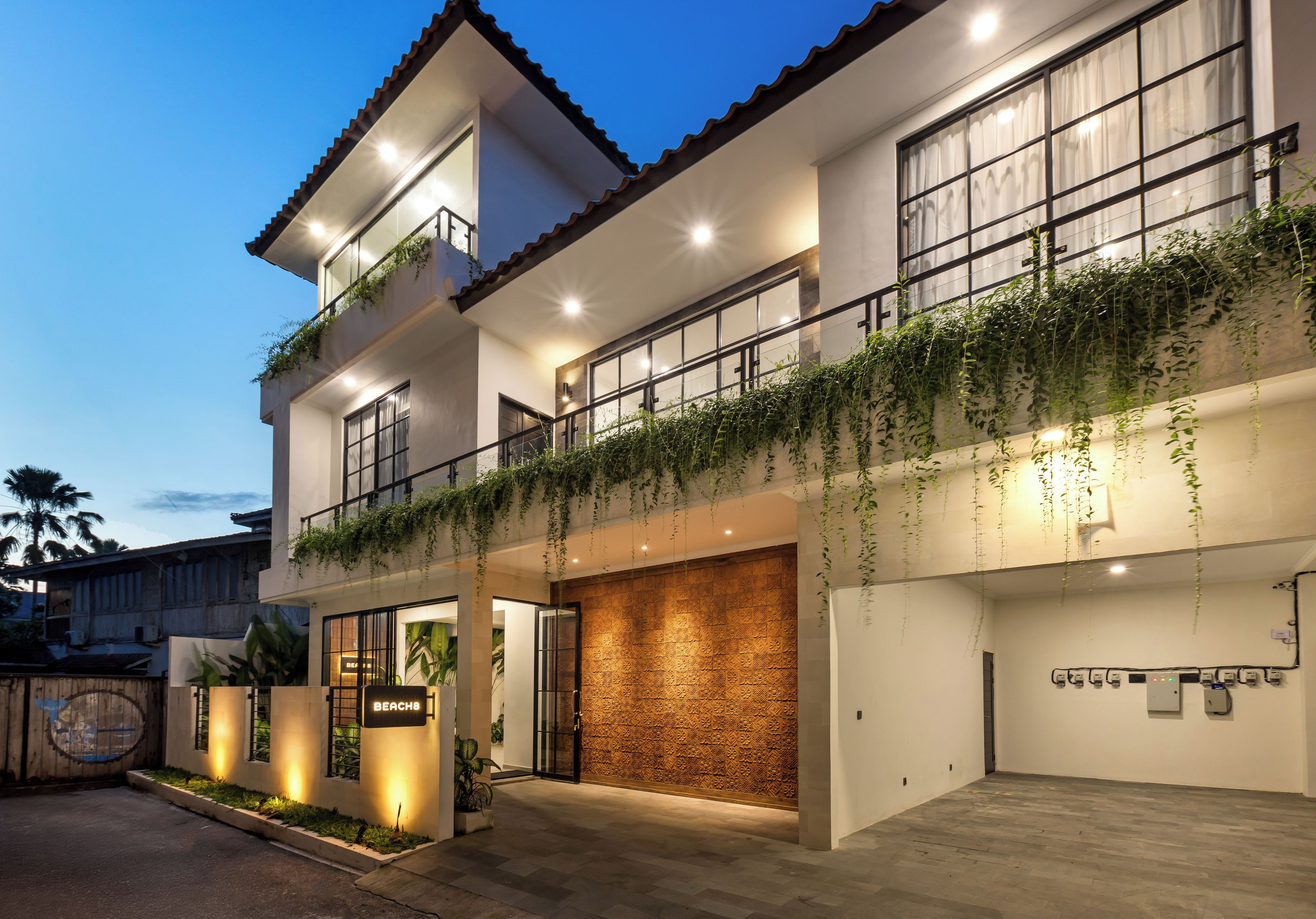 Un edificio moderno de dos pisos con balcón, garaje y un letrero que dice 'BEACH'.