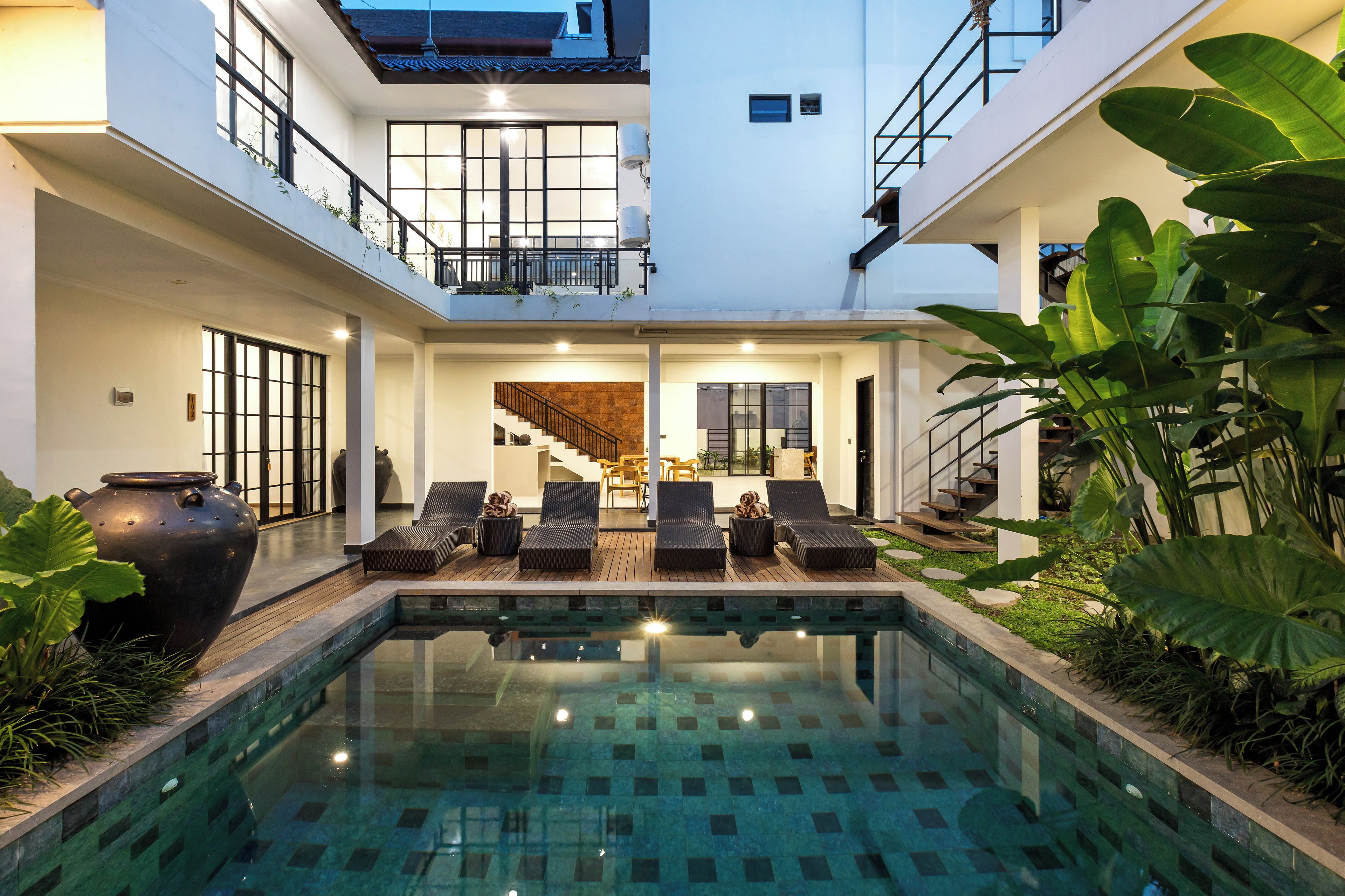 A modern pool area with lounge chairs and a view of the interior.