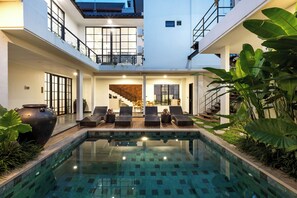Ein moderner Poolbereich mit Liegestühlen und Blick ins Innere.