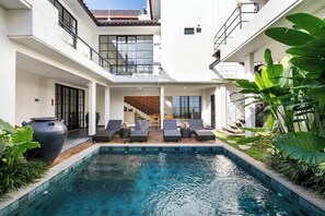 A modern house with a swimming pool, a staircase, and lounge chairs. - Beach8 Canggu By Kerta Living (Canggu)