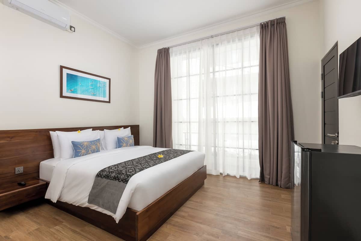 Een hotelkamer met een houten bed, een flatscreen-televisie en een groot raam met gordijnen.