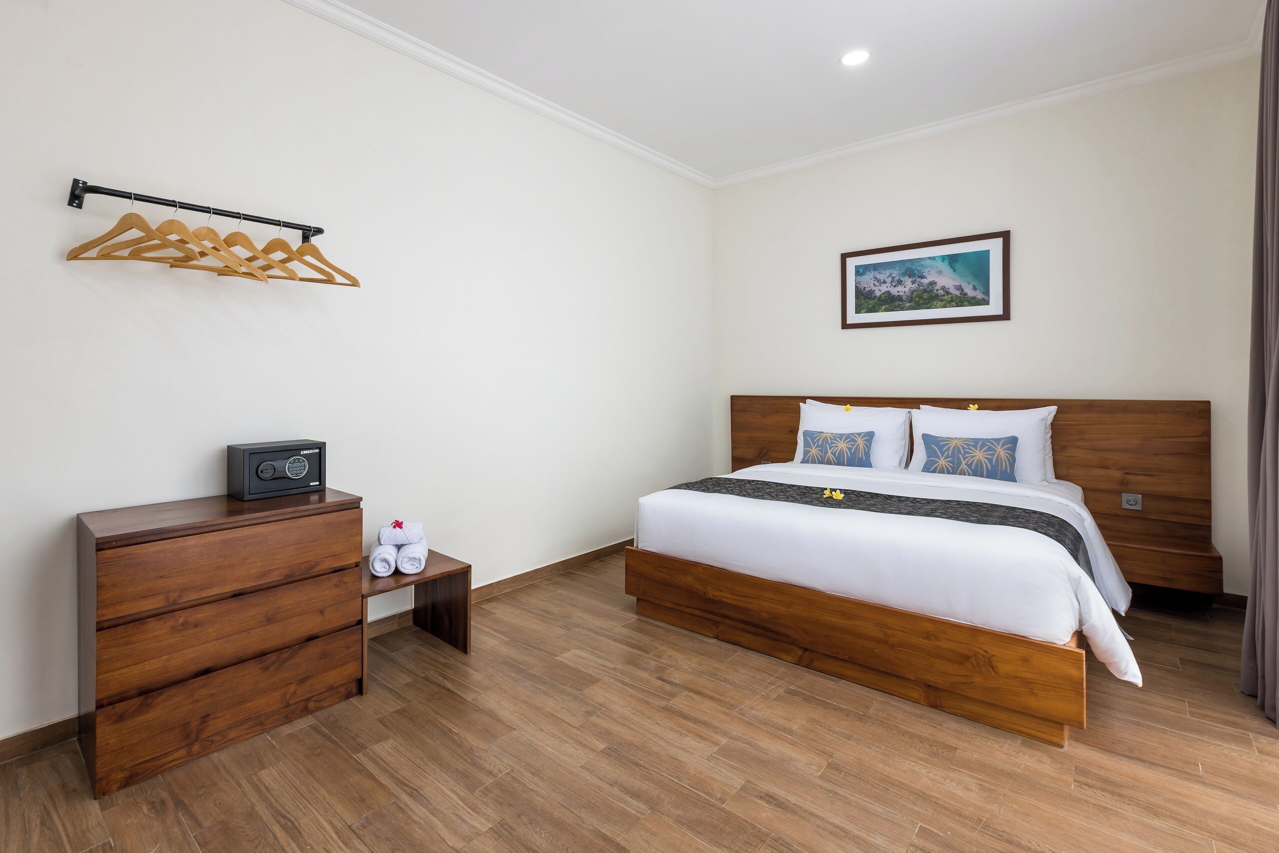 Een hotelkamer met een houten bed, een nachtkastje, een kast en een kapstok.