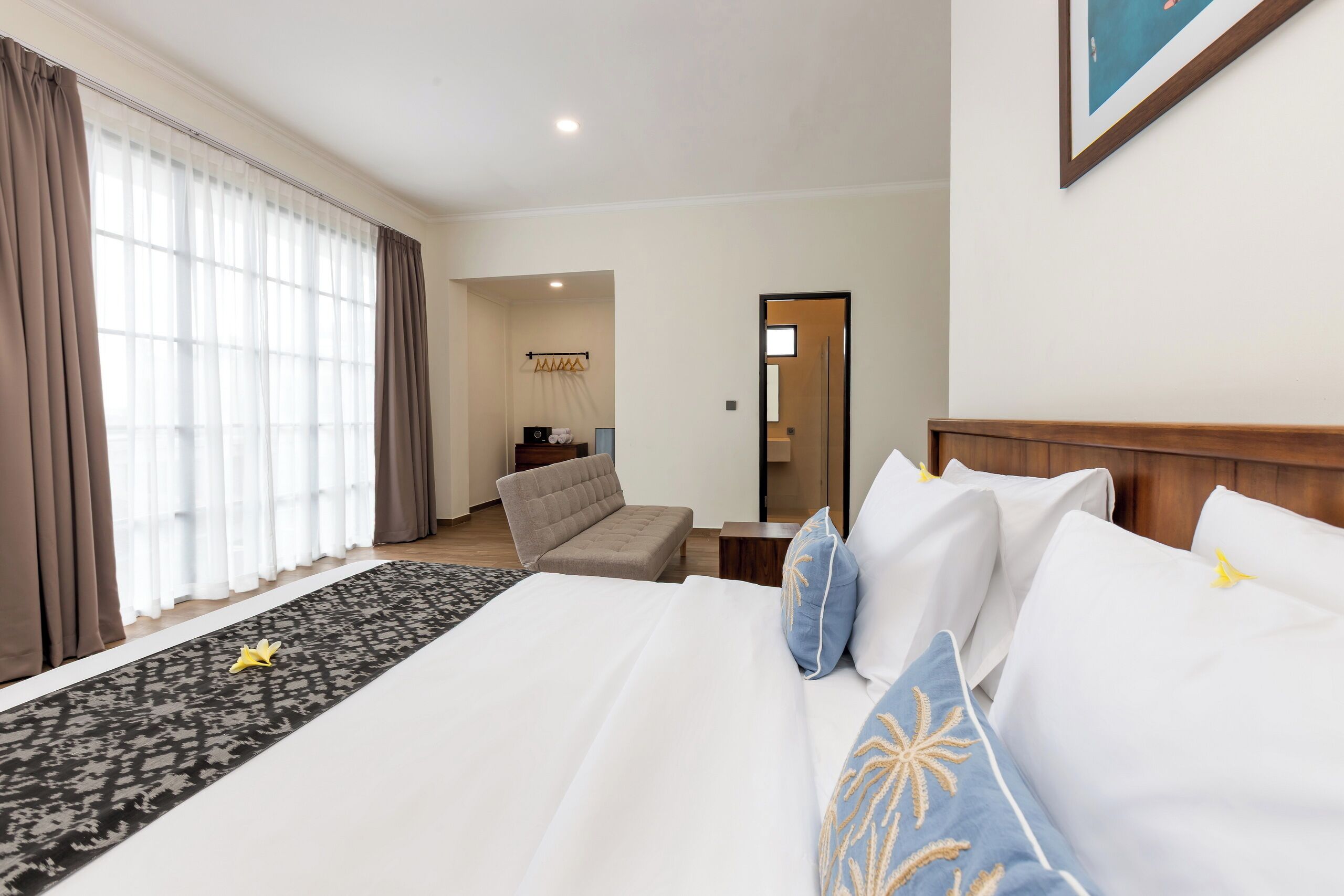 Una habitación de hotel con una cama grande, un sofá, una mesita y un espejo.
