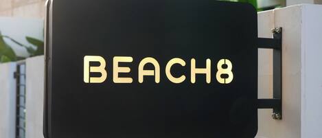 A black sign with the text "BEACH8" mounted on a white wall.
