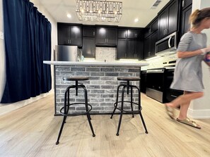 A modern kitchen with dark cabinets, a marble backsplash, and a central island with stools. - The Lonestar landing is a Delightful 2 bedroom townhome in San Angelo (San Angelo)