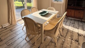 Een eetruimte met een tafel, stoelen, een plafondventilator en uitzicht op de omgeving.