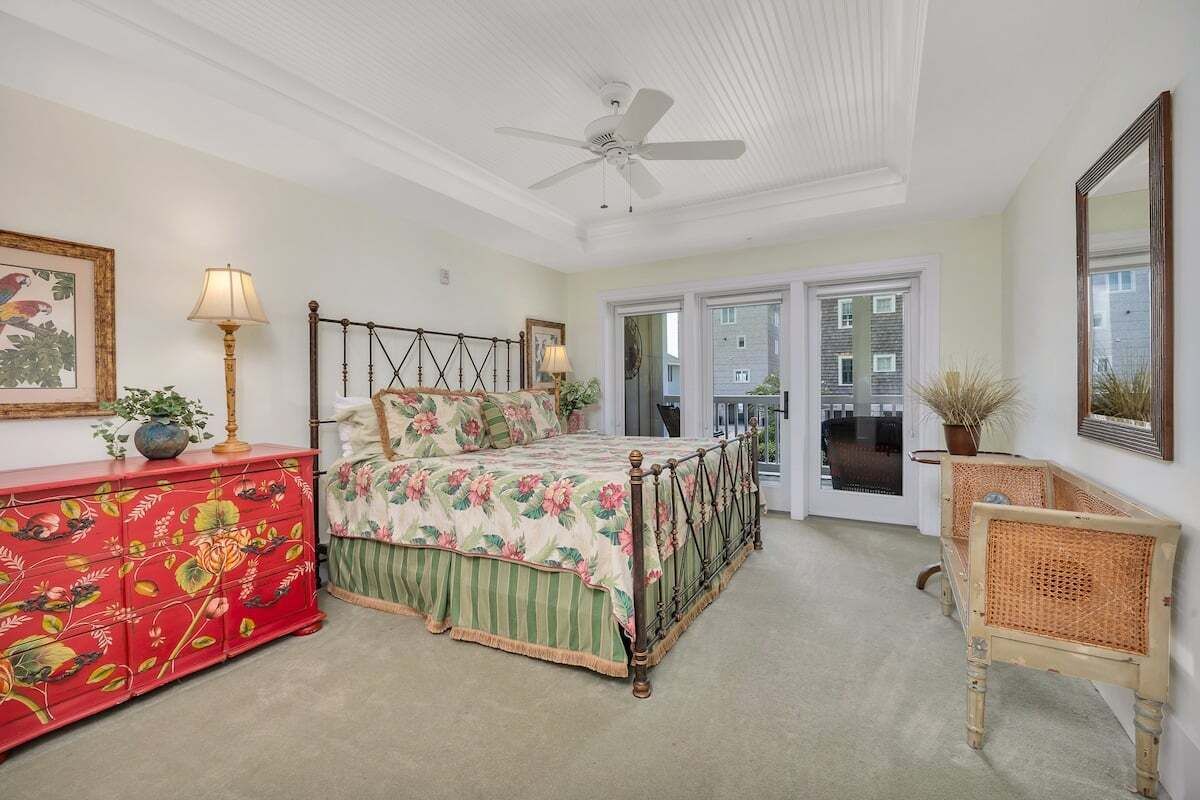 A bedroom with a bed, a dresser, a chair, and a ceiling fan.