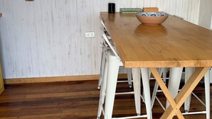 A wooden dining table with a bowl on it, white chairs, and a ceiling fan. - Tiny house Pilolcura (Valdivia)