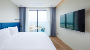 Habitación de hotel con una cama grande, un televisor en la pared y vistas a la ciudad por la ventana.