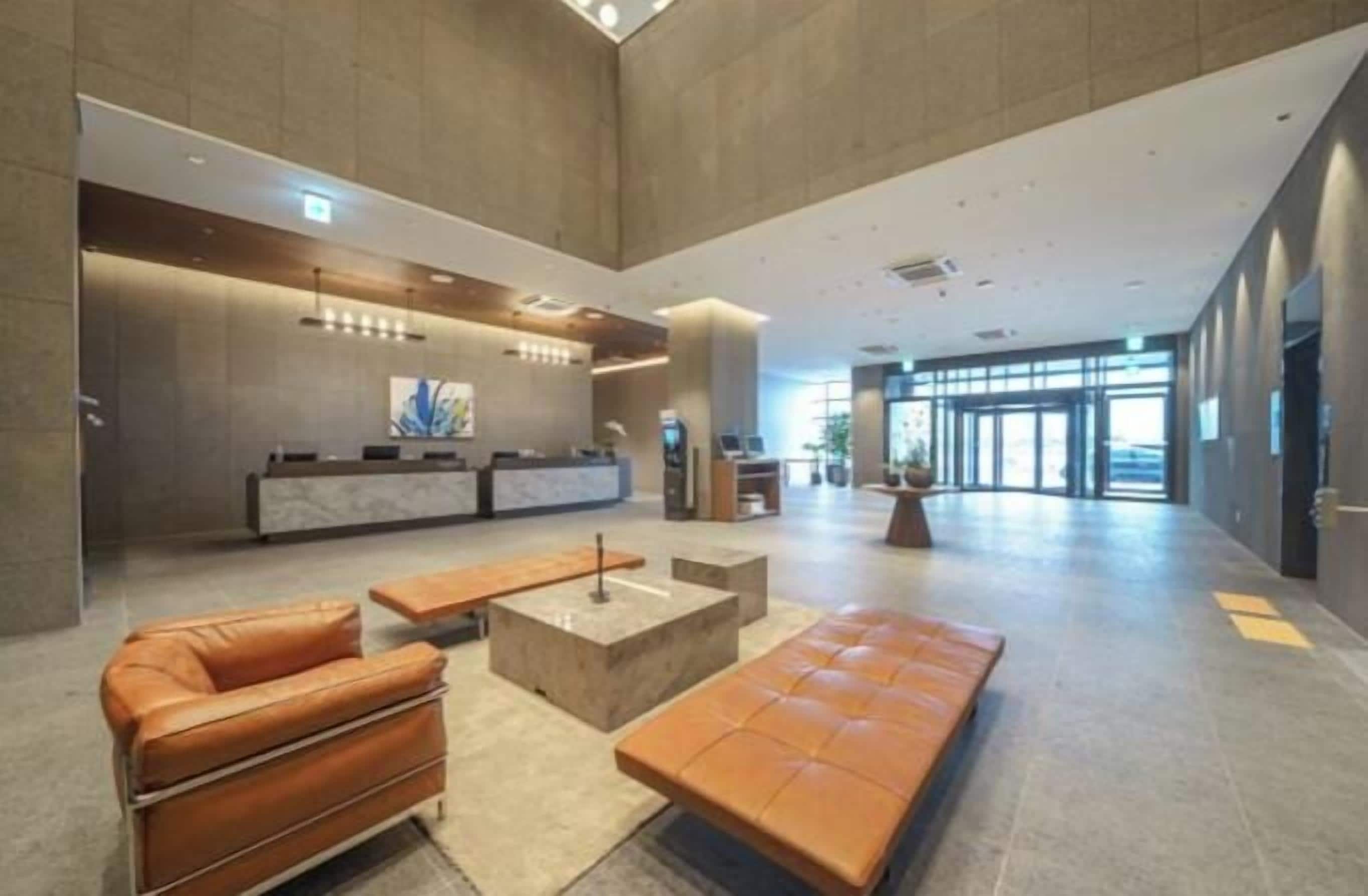 Een ruime lobby met een receptiebalie, een zithoek en een groot raam dat voor daglicht zorgt.
