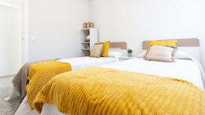 Ein Hotelzimmer mit zwei Betten, einem weißen Schrank, einer kleinen Ablage mit Dekoration und einer Tür.
