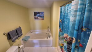A bathroom with a bathtub, toilet, and shower curtain.