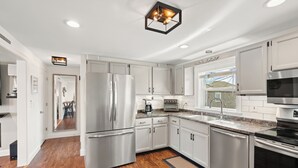 A modern kitchen with stainless steel appliances, white cabinetry, and a wooden floor. - Beautiful, Large 3-bedroom luxury apartment 300' from Salisbury Beach (Salisbury)