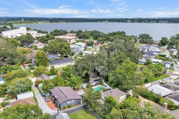 A residential area with houses, a swimming pool, and a large body of water in the background. - Walk to Lakes & Florida Southern | Pet-Friendly | 2BR, BBQ Patio, Sleeps 4 (Lakeland)