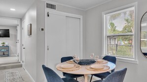 A dining area with a round table set for four, blue chairs, and a window with blinds. - Walk to Lakes & Florida Southern | Pet-Friendly | 2BR, BBQ Patio, Sleeps 4 (Lakeland)