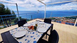 Une table dressée pour deux personnes, avec vue sur la mer et une ville en arrière-plan.