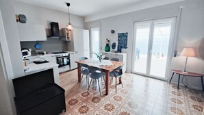 Une cuisine moderne avec des meubles blancs, une cuisinière noire et un coin repas comprenant une table et des chaises en bois.