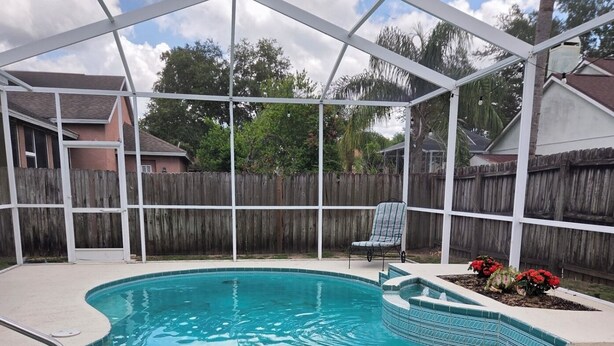 A covered swimming pool with a wooden deck and a chair.