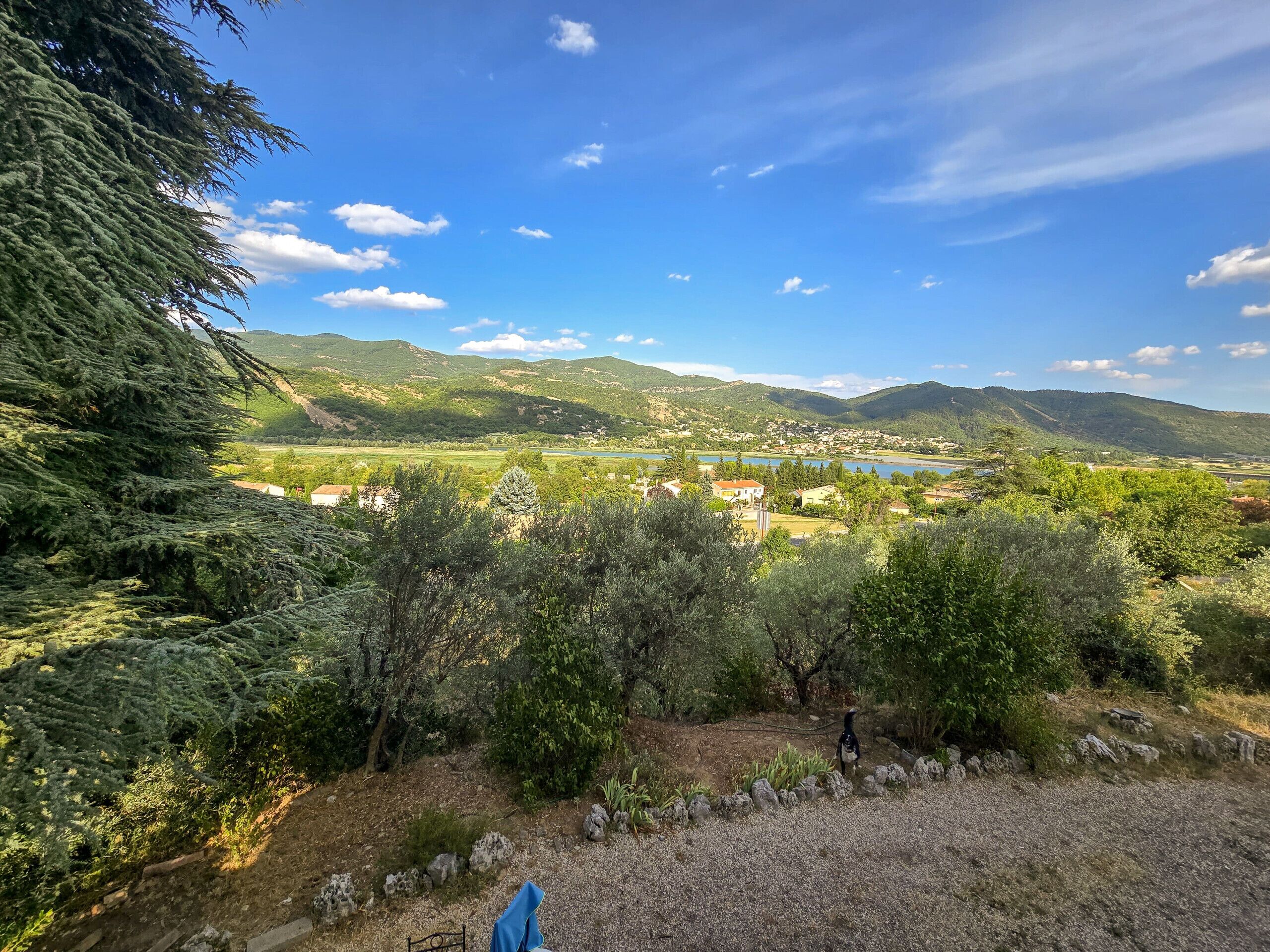 A scenic view of a mountainous area with a lake, houses, and trees.