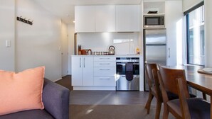 Een kleine keuken met witte kastjes, een magnetron en een inbouwoven.