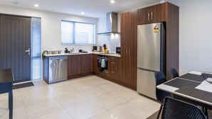 A modern kitchen with wooden cabinets, stainless steel appliances, and a dining area with a table and chairs. - 3bed with Garage Minutes from the Action and Sleeps 8 (Christchurch)