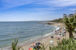 A beach with umbrellas, people, and a clear sky. - Private Rooftop Terrace with Bar & Pool near to Torrequebrada Beach (Benalmádena)