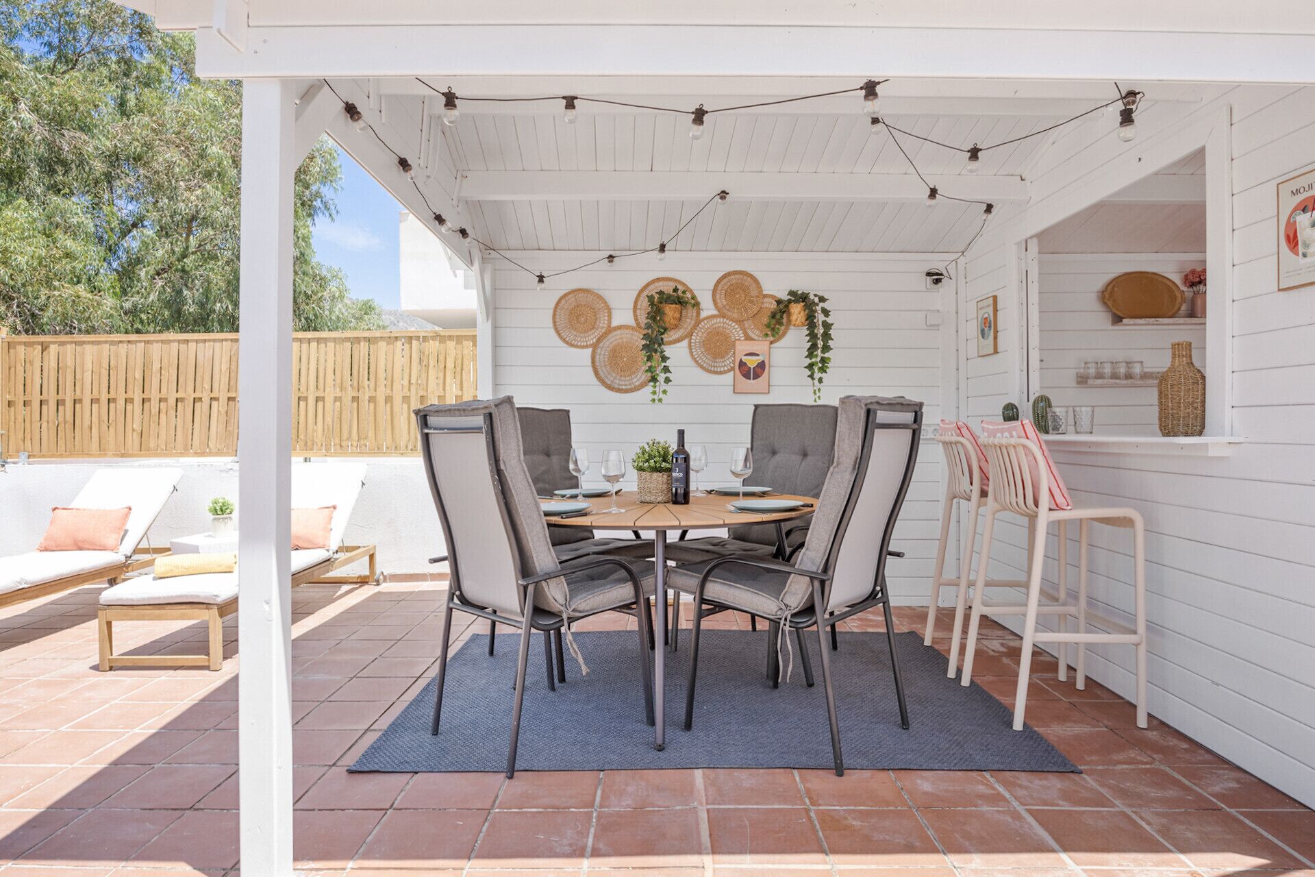 A covered patio with a round table, chairs, and string lights.