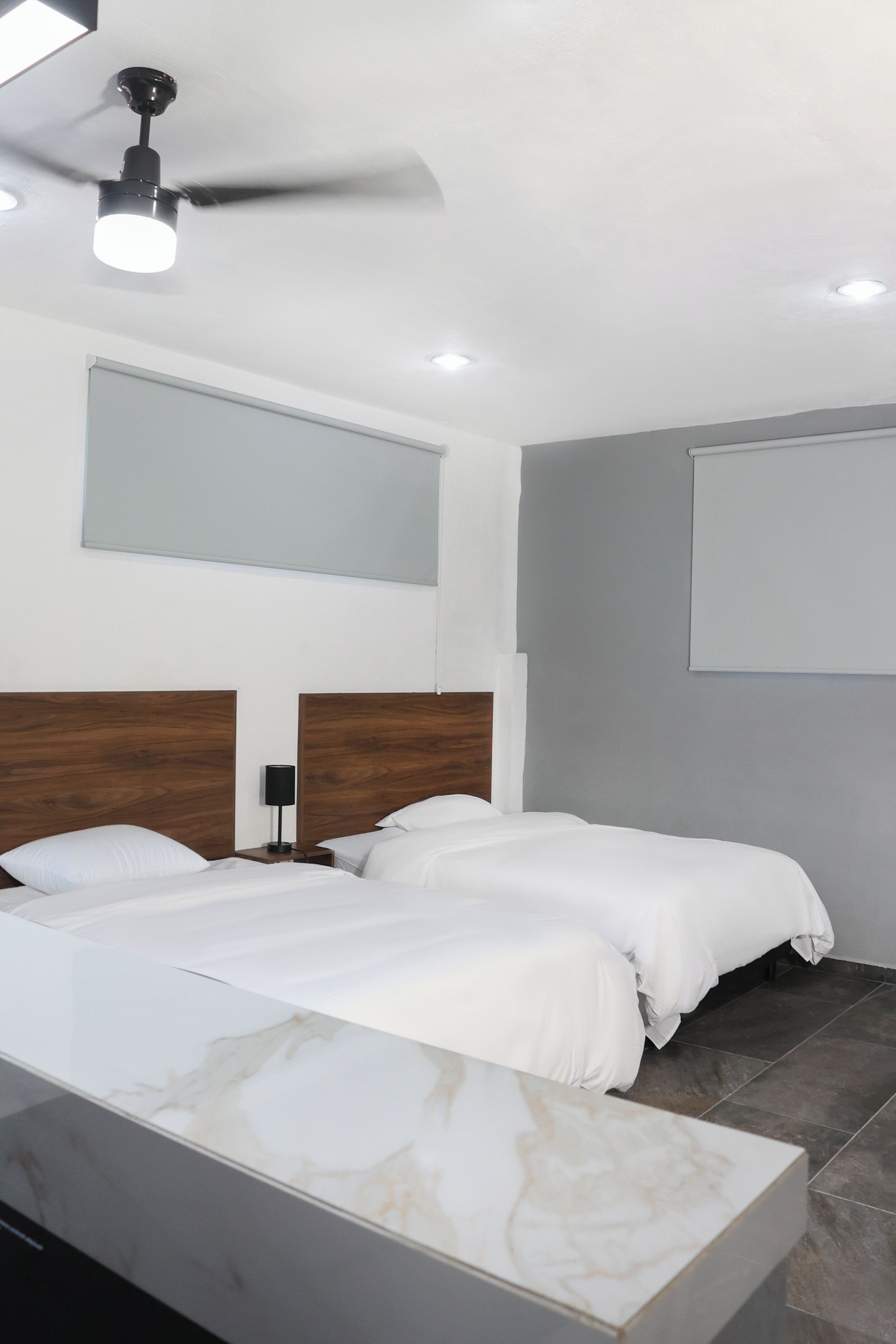 A modern hotel room with a large bed, a ceiling fan, and a large window.