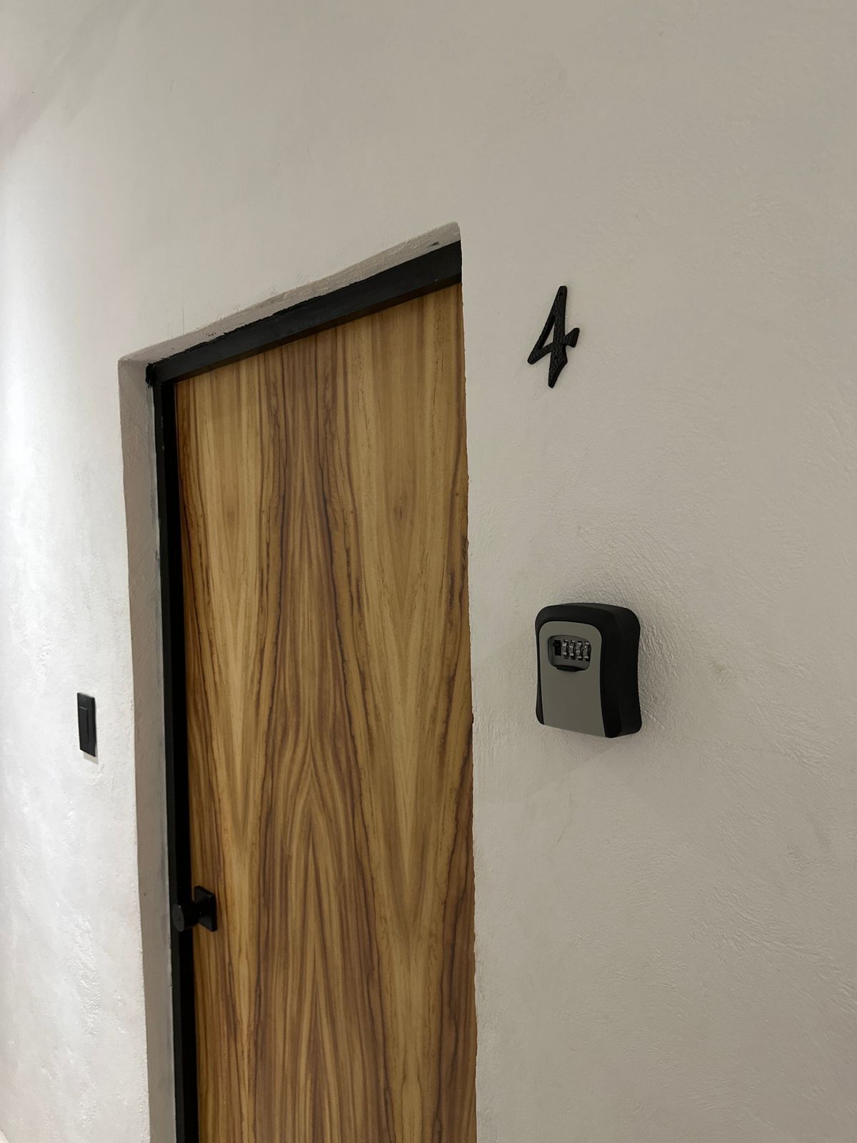 Una puerta de madera con marco negro y un dispositivo de seguridad fijado a la pared.
