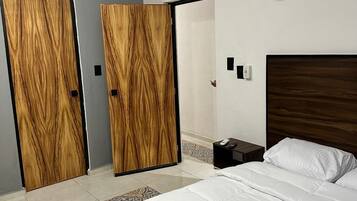 Un dormitorio con una cama grande, un armario de madera y una mesita de noche con un control remoto.