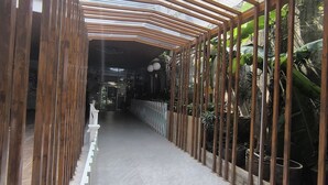 A corridor with a wooden structure on the left and a plant-covered wall on the right. - Hotel Bunga Bunga (Jakarta)