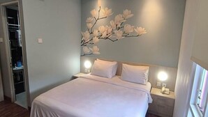 A bedroom with a bed, nightstands, a wall-mounted light, and a closet. - Hotel Bunga Bunga (Jakarta)