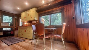A wooden cabin interior with a kitchen area, dining table, and chairs. - McCall Me Cozy, McCall Me Cozy (Valley County)