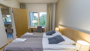 Une chambre d’hôtel avec deux lits, un bureau et une chaise.