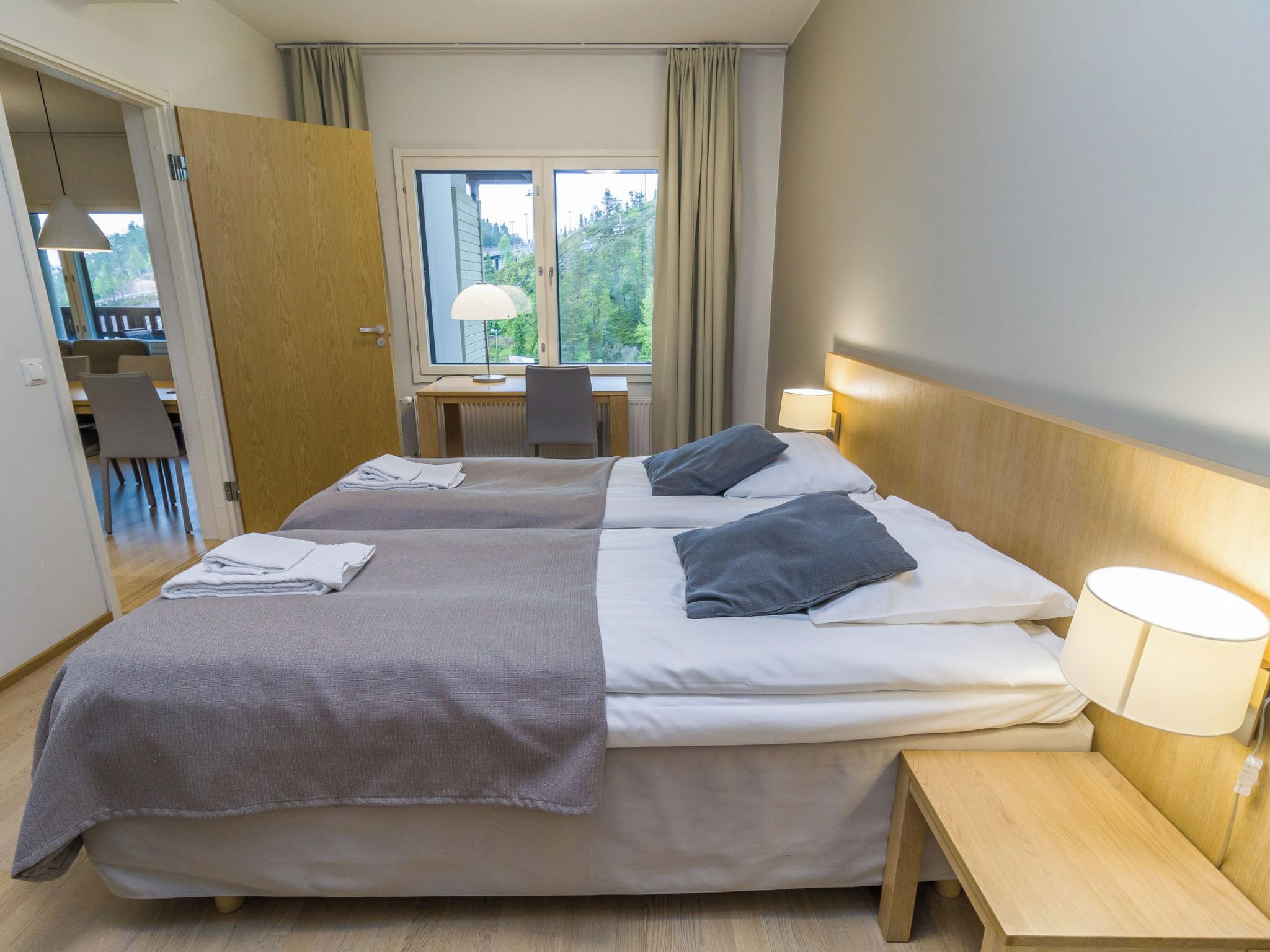 A hotel room with two beds, a desk, and a chair.