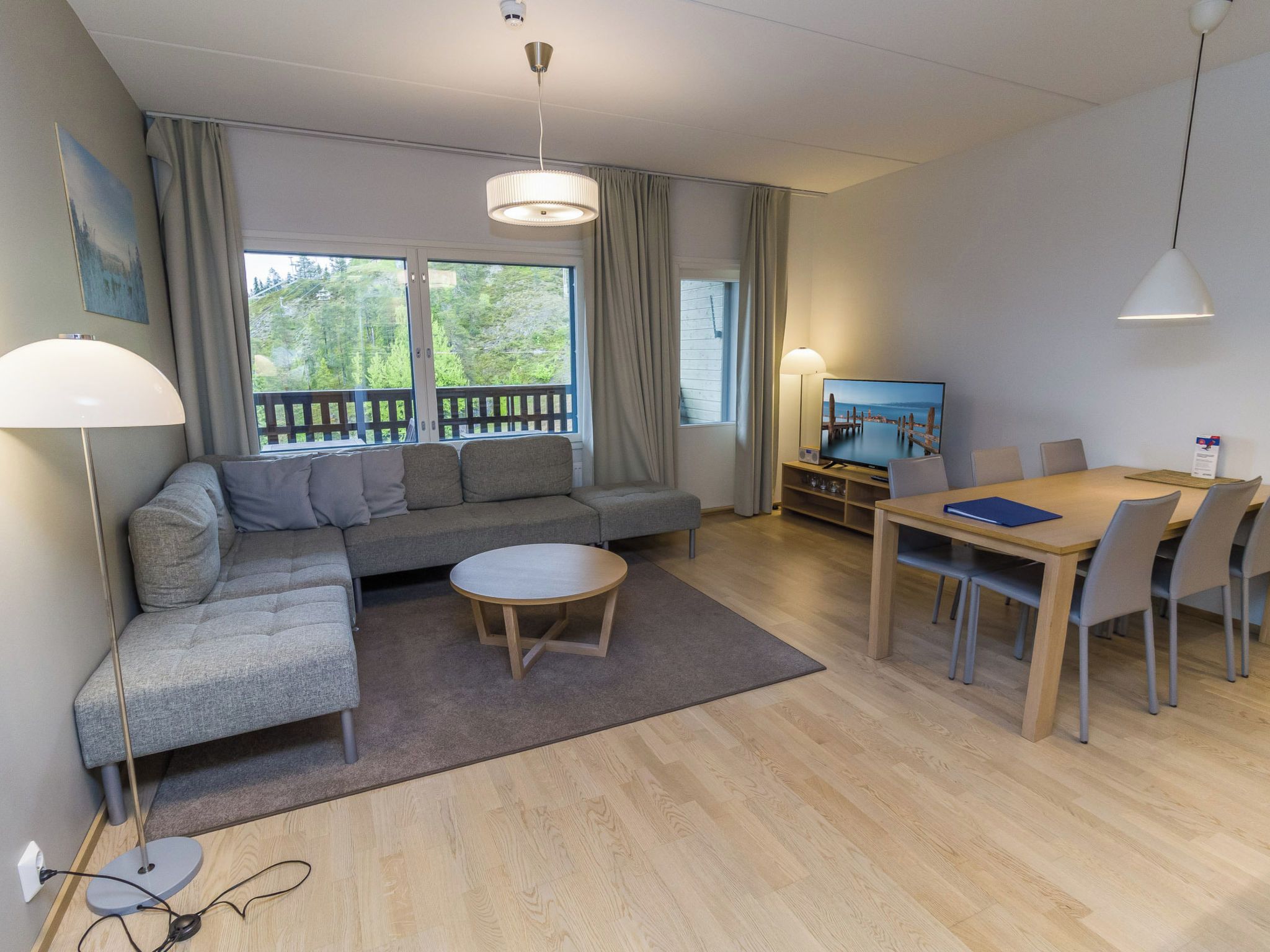Een moderne woonkamer met een bank, een salontafel, een eettafel met stoelen en een televisie.